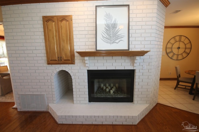 details with a fireplace, wood finished floors, visible vents, and crown molding