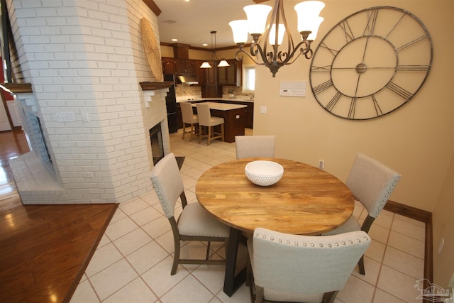 dining room featuring a brick fireplace, light tile patterned floors, a chandelier, and recessed lighting