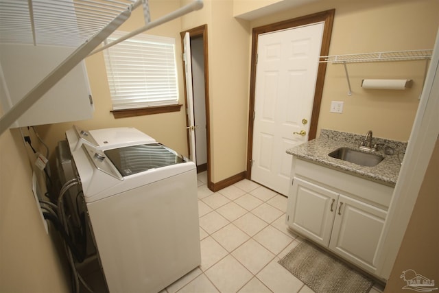 washroom featuring washing machine and clothes dryer, light tile patterned flooring, a sink, laundry area, and baseboards