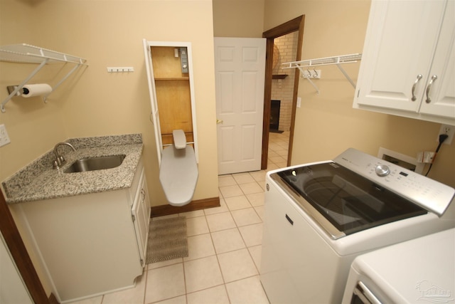 laundry room with light tile patterned floors, cabinet space, a sink, washer and dryer, and baseboards