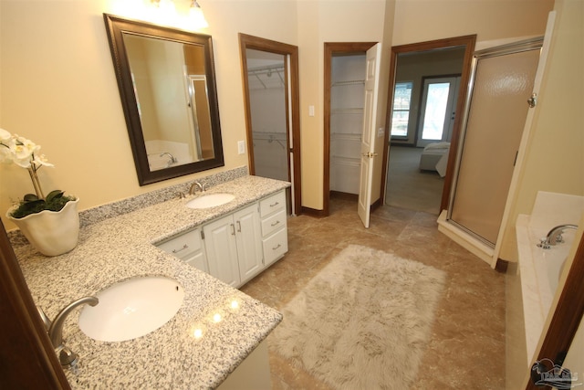 full bath featuring double vanity, a garden tub, a walk in closet, a shower stall, and a sink