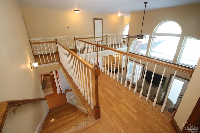 stairway featuring ceiling fan, wood finished floors, and a towering ceiling