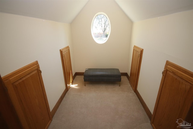 interior space featuring vaulted ceiling, baseboards, and light colored carpet