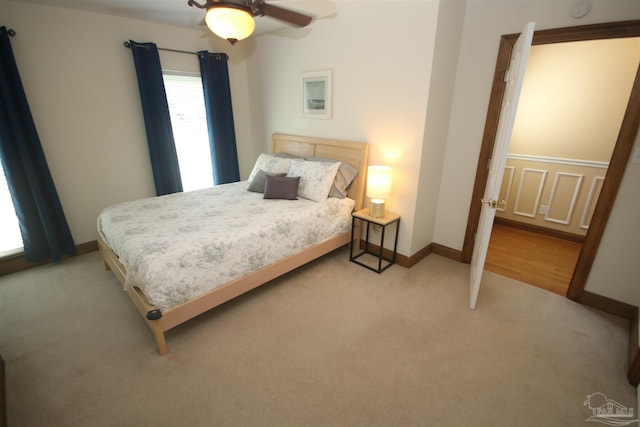 bedroom featuring light carpet, baseboards, and a ceiling fan