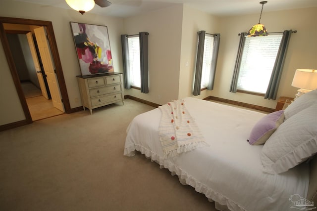 bedroom with light colored carpet, multiple windows, and baseboards