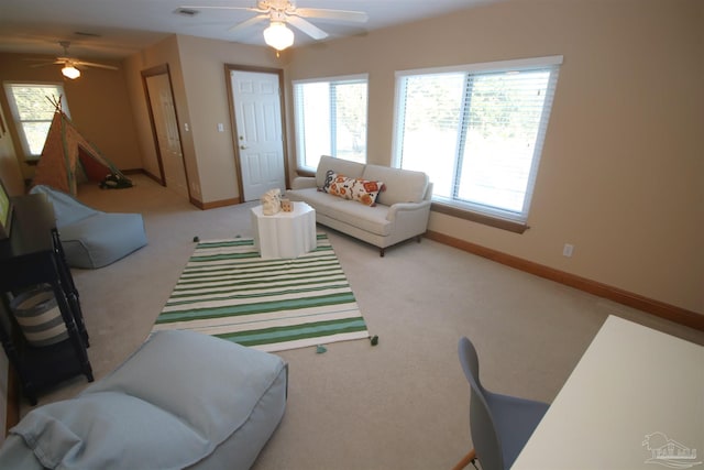 carpeted living room with baseboards and a ceiling fan