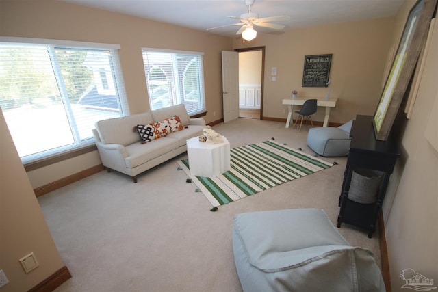 living area featuring carpet flooring, ceiling fan, and baseboards