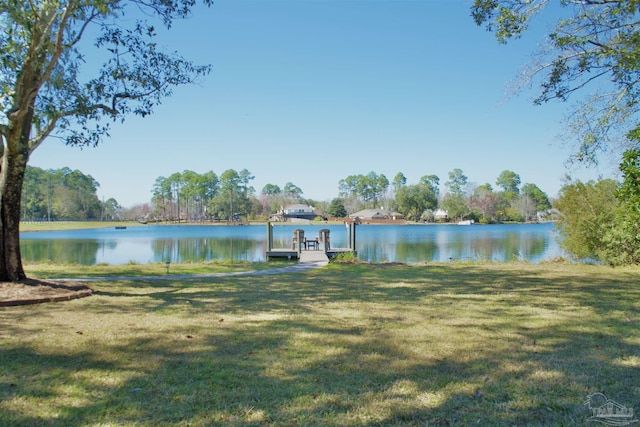 view of dock with a lawn and a water view