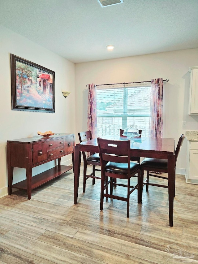 dining space featuring light wood finished floors and baseboards