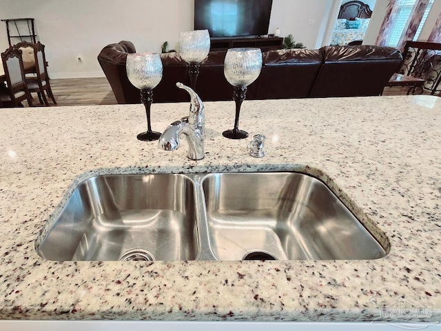 interior details with light stone countertops, baseboards, a sink, and wood finished floors