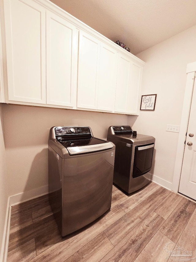 laundry area featuring light wood-type flooring, cabinet space, baseboards, and independent washer and dryer