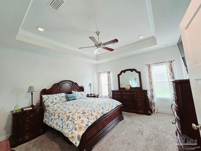 bedroom with multiple windows, visible vents, and a raised ceiling