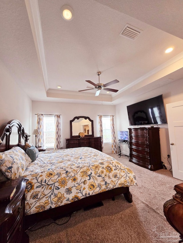 bedroom with carpet, multiple windows, visible vents, and a tray ceiling