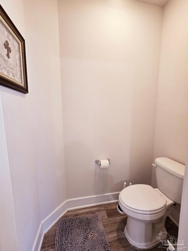 bathroom featuring toilet, baseboards, and wood finished floors