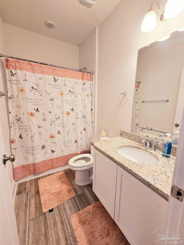 bathroom featuring toilet, a shower with shower curtain, wood finished floors, and vanity