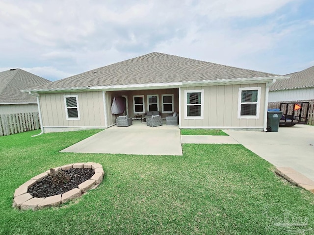 rear view of house featuring roof with shingles, a patio, a lawn, board and batten siding, and fence