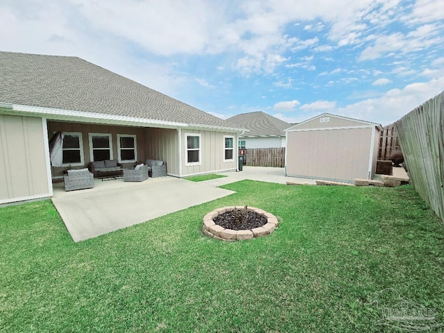 view of yard with an outdoor living space with a fire pit, a patio, a fenced backyard, an outbuilding, and a storage unit