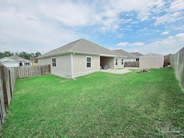 rear view of property with a fenced backyard, an outbuilding, a lawn, and a patio