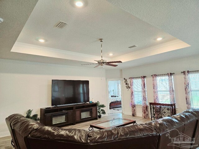 living room with a textured ceiling, a raised ceiling, and visible vents