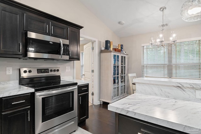 kitchen with vaulted ceiling, appliances with stainless steel finishes, hanging light fixtures, a notable chandelier, and dark wood-type flooring