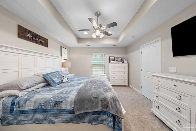 carpeted bedroom with a tray ceiling and ceiling fan