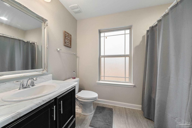 bathroom with wood-type flooring, plenty of natural light, vanity, and toilet