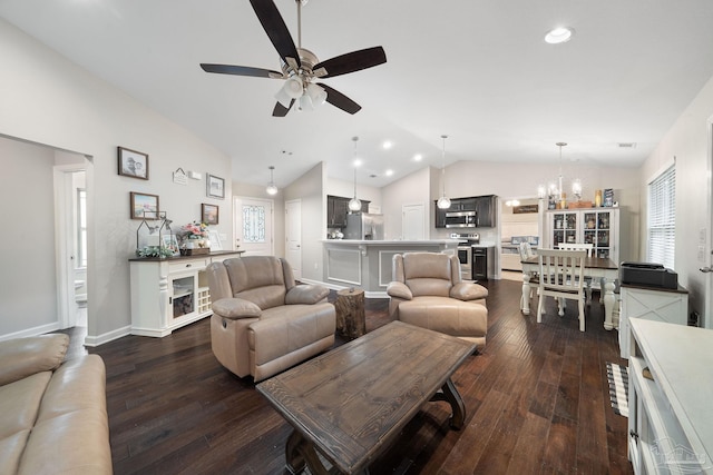 living room featuring lofted ceiling, ceiling fan with notable chandelier, plenty of natural light, and dark hardwood / wood-style floors