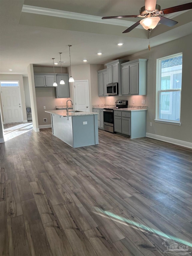 kitchen with a kitchen island with sink, hanging light fixtures, gray cabinets, appliances with stainless steel finishes, and dark hardwood / wood-style flooring