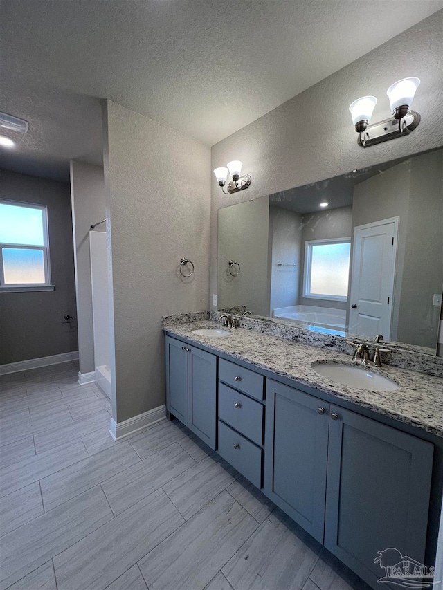 bathroom featuring vanity, a healthy amount of sunlight, and a textured ceiling