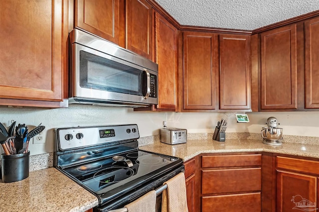 kitchen with light stone counters, a textured ceiling, and stainless steel appliances