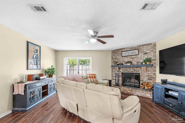 living room with ceiling fan, a brick fireplace, and a textured ceiling