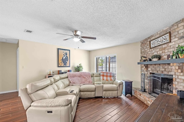 living room with ceiling fan, a fireplace, and a textured ceiling