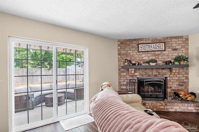 living room with a brick fireplace, plenty of natural light, and a textured ceiling