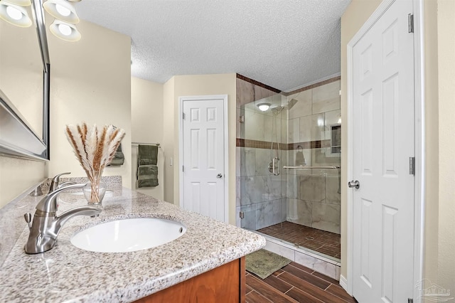 bathroom featuring a textured ceiling, walk in shower, and vanity