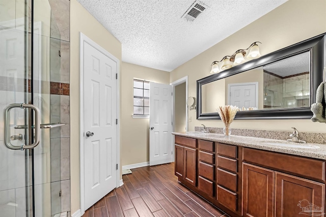 bathroom featuring vanity, a shower with door, and a textured ceiling