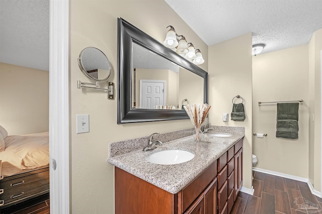 bathroom featuring a textured ceiling, toilet, and vanity