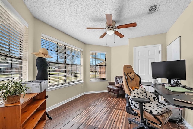 office space with ceiling fan, dark wood-type flooring, a textured ceiling, and a healthy amount of sunlight