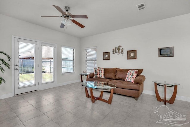 living area with light tile patterned floors, a ceiling fan, visible vents, and baseboards