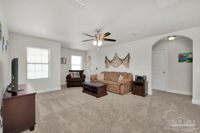 living room featuring light colored carpet, arched walkways, visible vents, and baseboards