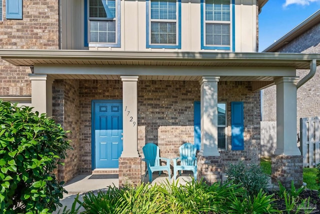 entrance to property with a porch and brick siding