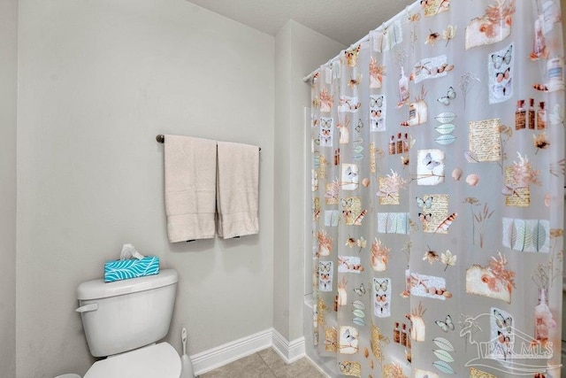 bathroom with a shower with shower curtain, tile patterned flooring, baseboards, and toilet