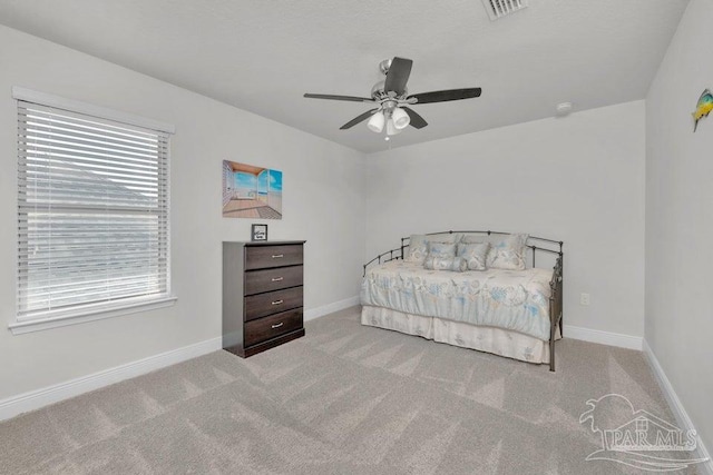 bedroom featuring visible vents, baseboards, a ceiling fan, and light colored carpet