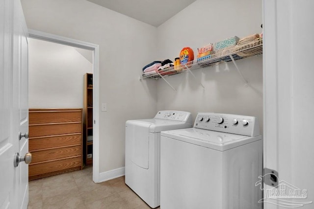 washroom featuring laundry area, light tile patterned flooring, baseboards, and washing machine and clothes dryer