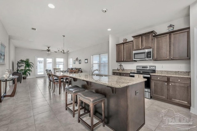 kitchen with a breakfast bar area, a sink, visible vents, appliances with stainless steel finishes, and an island with sink