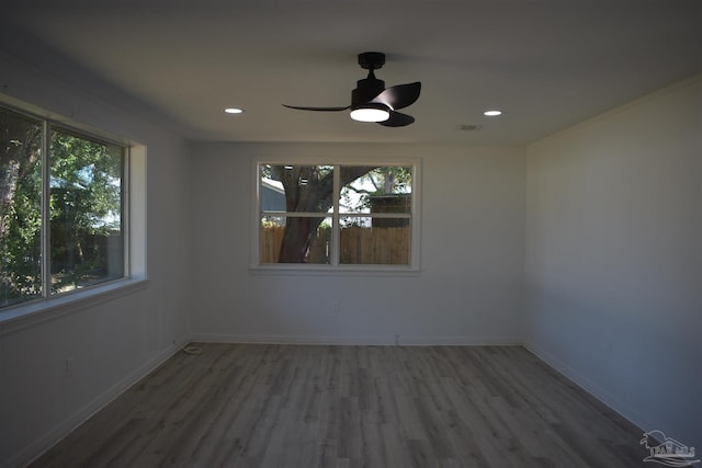 unfurnished room featuring wood finished floors, plenty of natural light, visible vents, and a ceiling fan