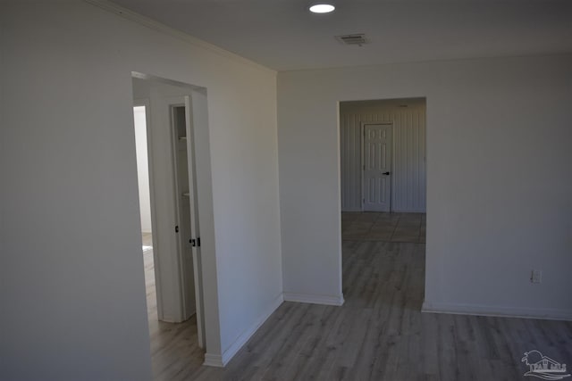 hallway featuring ornamental molding, visible vents, wood finished floors, and baseboards