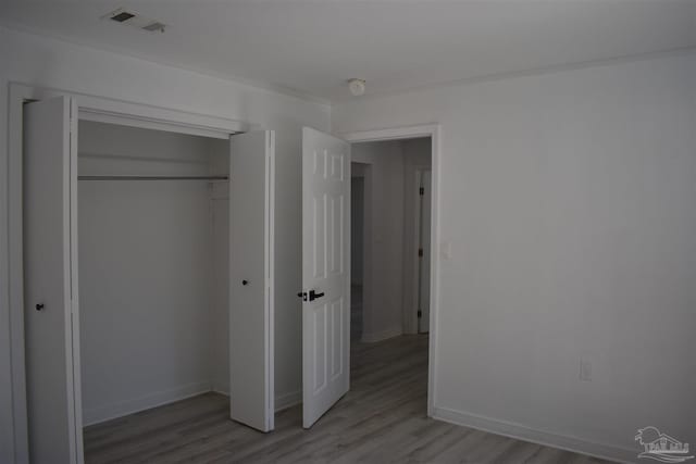 unfurnished bedroom with visible vents, baseboards, light wood finished floors, and a closet
