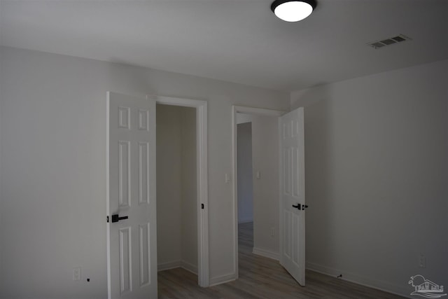 unfurnished bedroom featuring baseboards, visible vents, and wood finished floors
