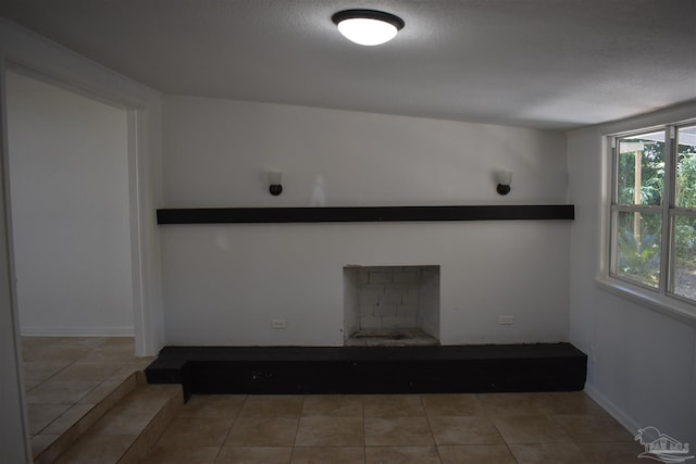 unfurnished living room with a textured ceiling, tile patterned flooring, and a fireplace
