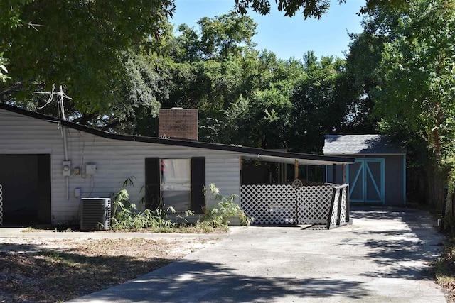 view of property exterior featuring an outdoor structure, a shed, central AC unit, and a chimney